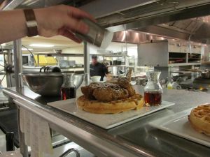 Chef Kelley Schmidt puts the finishing touches on an order of chicken & waffles.